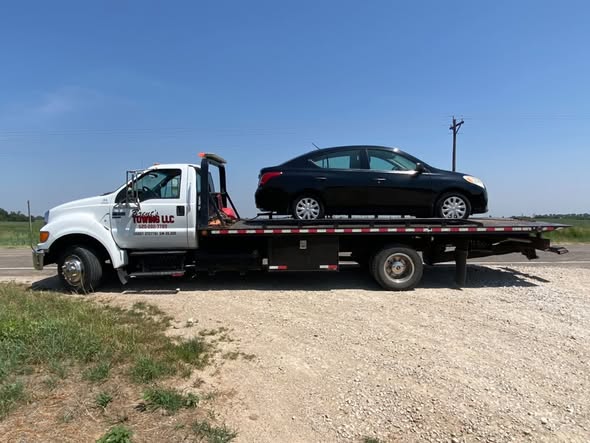 Brent's Towing flatbed truck hauling a sedan on a Kansas highway